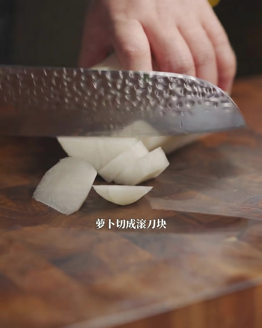 도마 위에서 칼로 무를 큼직하게 썰고 있는 모습.