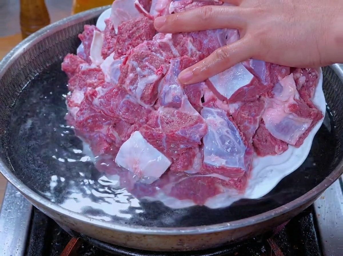 데치기 위해 물이 든 냄비에 담그는 과정의 소고기 조각들.