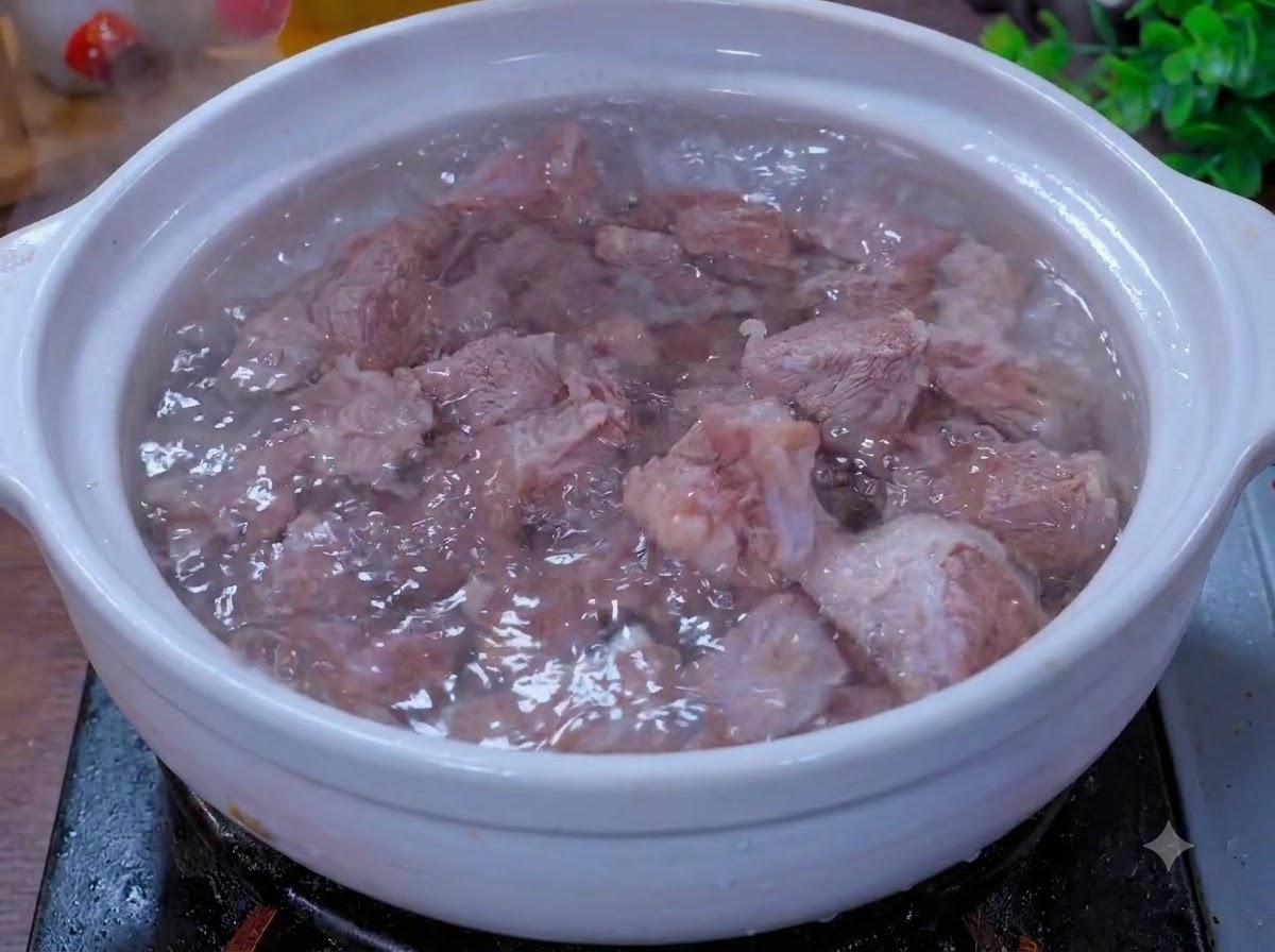 향신료와 함께 하얀 토기 냄비 안에서 끓고 있는 소고기 조각들.