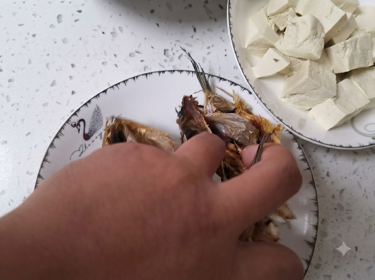 맑은 물이 담긴 그릇에서 손질한 북어 대가리를 씻는 모습.