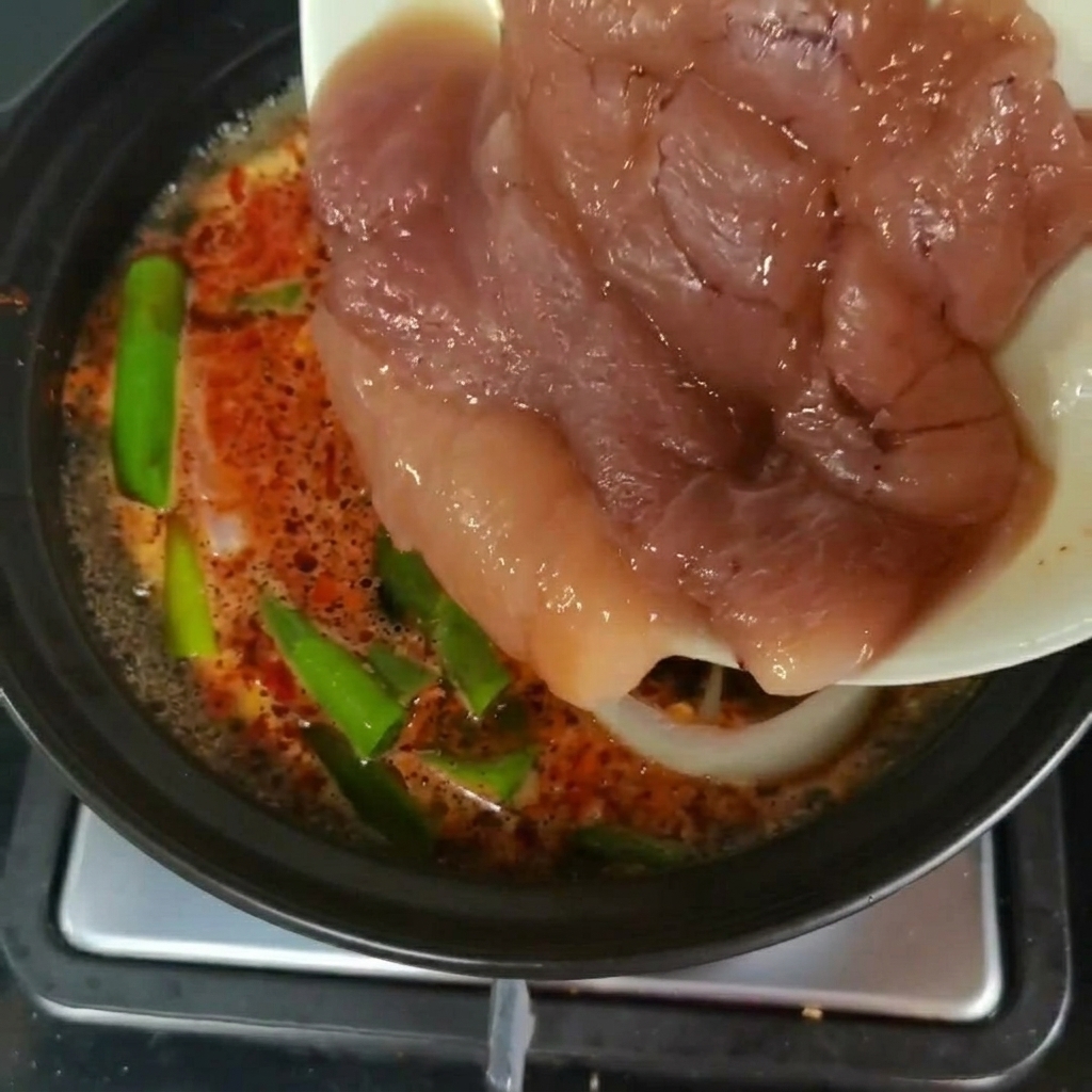 미리 썰어둔 명란을 파와 채소가 들어간 끓는 찌개에 조심스럽게 넣는 모습.