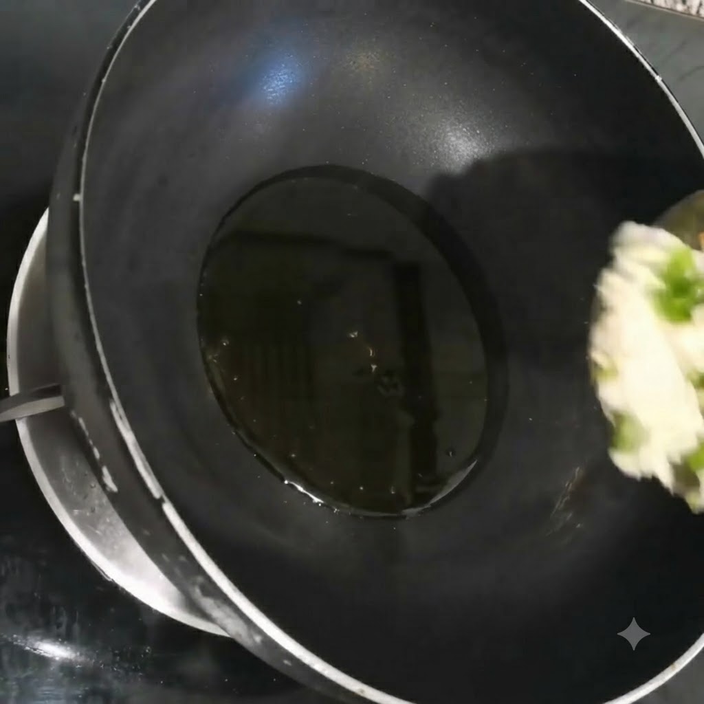 검은색 웍 안에서 뜨거운 기름에 잘게 썬 쪽파, 마늘, 고수가 지글지글 볶아지고 있는 모습.