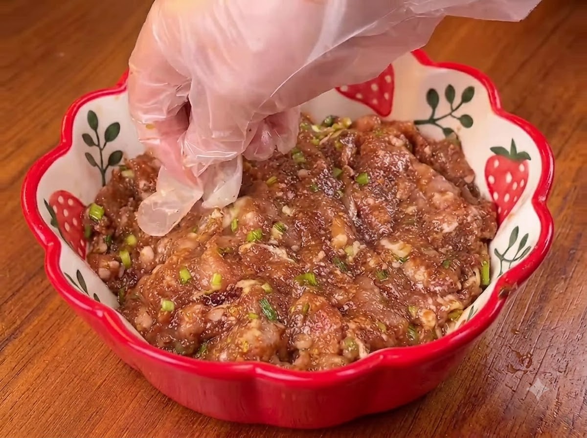 나무 도마 위에서 밀대를 이용해 둥근 반죽을 얇고 넓게 밀어 펴는 모습.