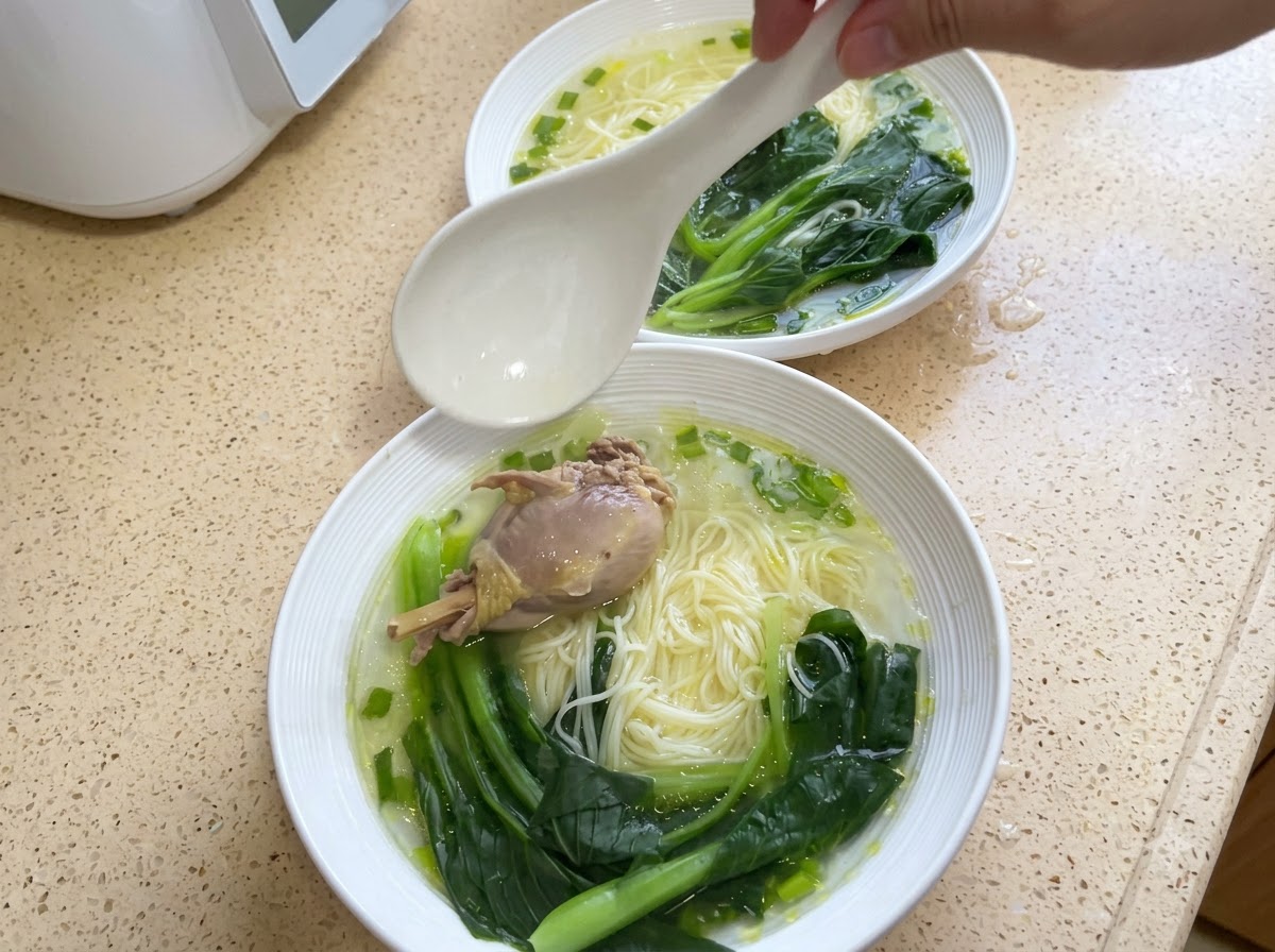 그릇에 담긴 국수 위에 닭고기 한 조각과 익힌 청경채가 얹어져 있는 모습.
