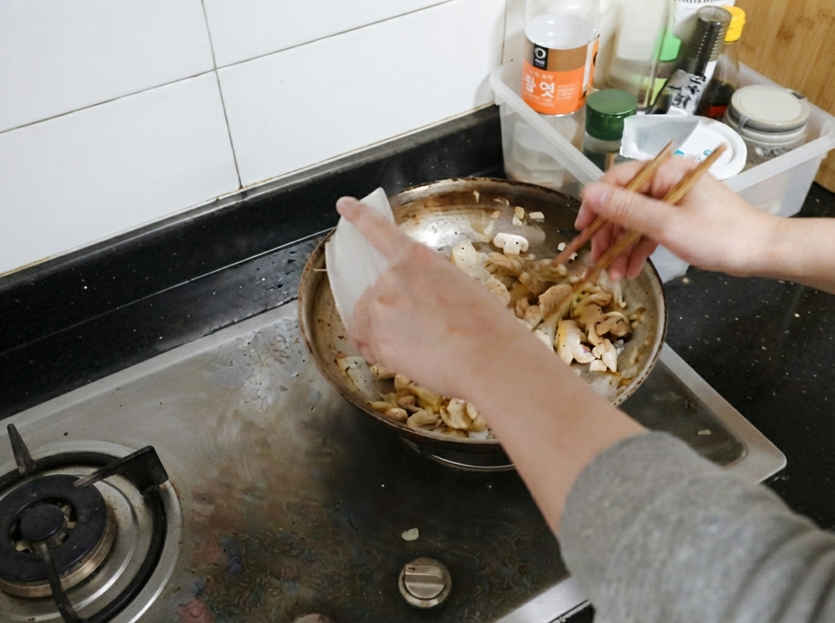 조리된 닭가슴살을 버섯과 양파가 있는 팬에 다시 넣는 모습.