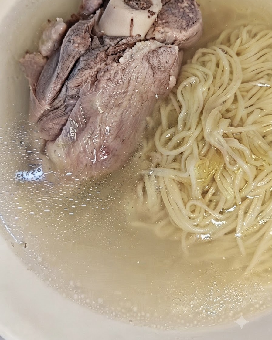 맑고 진한 돼지 육수와 함께 그릇에 담긴 삶은 면