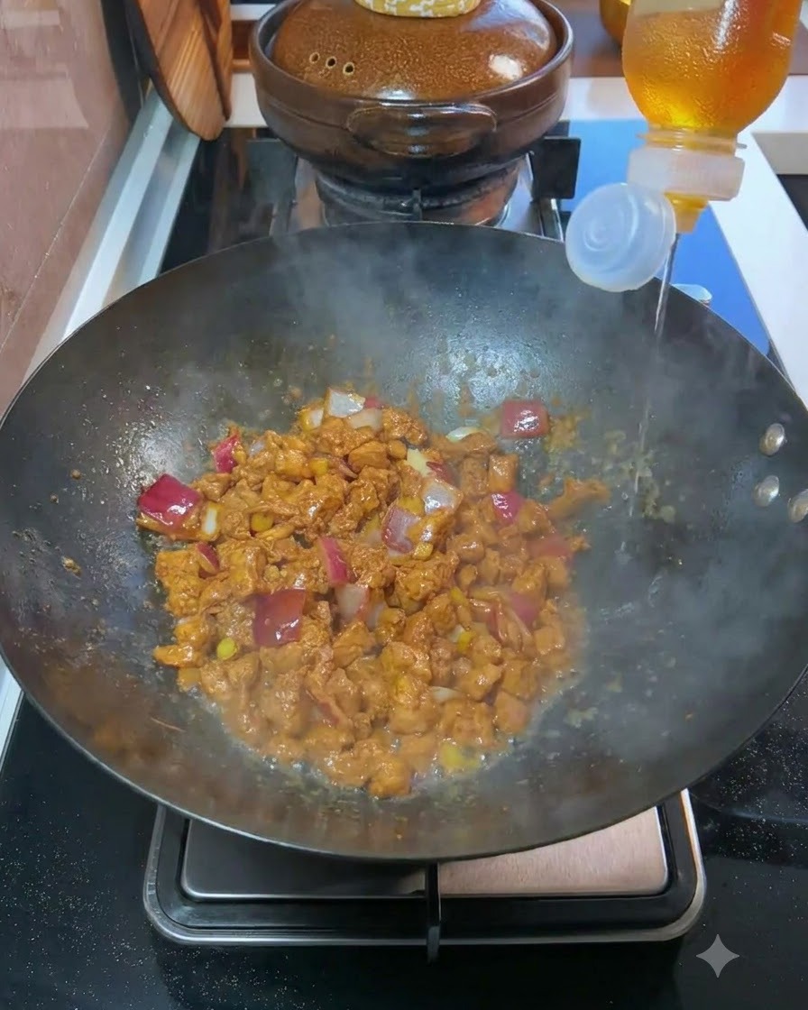 요리가 된 고기와 다진 양파가 담긴 웍에 병에서 맛술이 부어지는 모습.