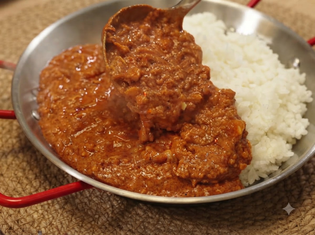 서빙 팬에 담긴 흰 쌀밥 위로 진한 카레 다진 고기 소스를 국자로 떠서 얹는 모습.