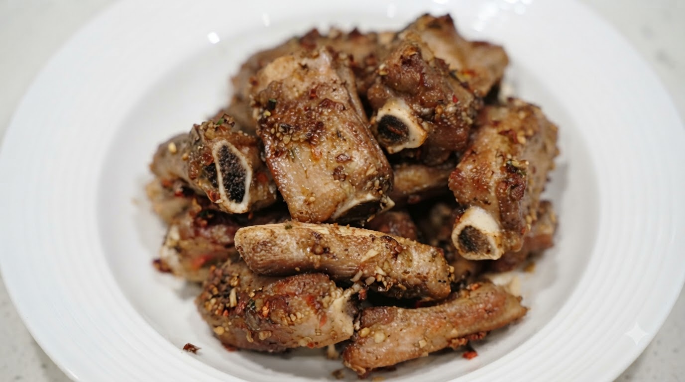 흰 접시 위에 먹음직스럽게 쌓인 마늘 쯔란 돼지갈비의 클로즈업 사진.