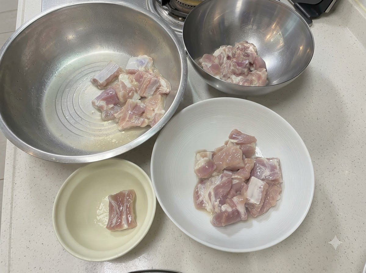 흰색 조리대 위에 다양한 메탈 및 도자기 그릇에 담긴 돼지갈비 조각들.