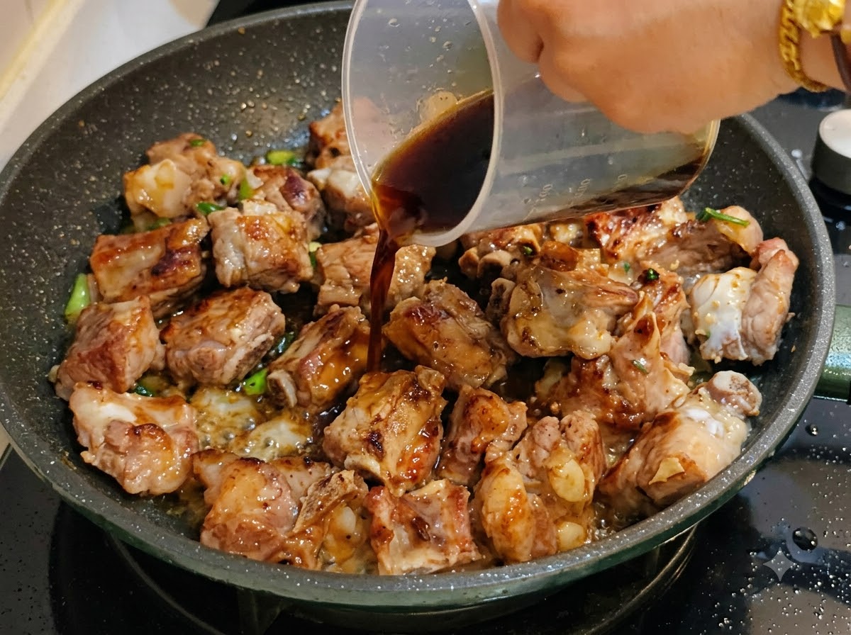 계량컵에서 돼지갈비가 있는 팬으로 진한 소스를 붓는 모습.