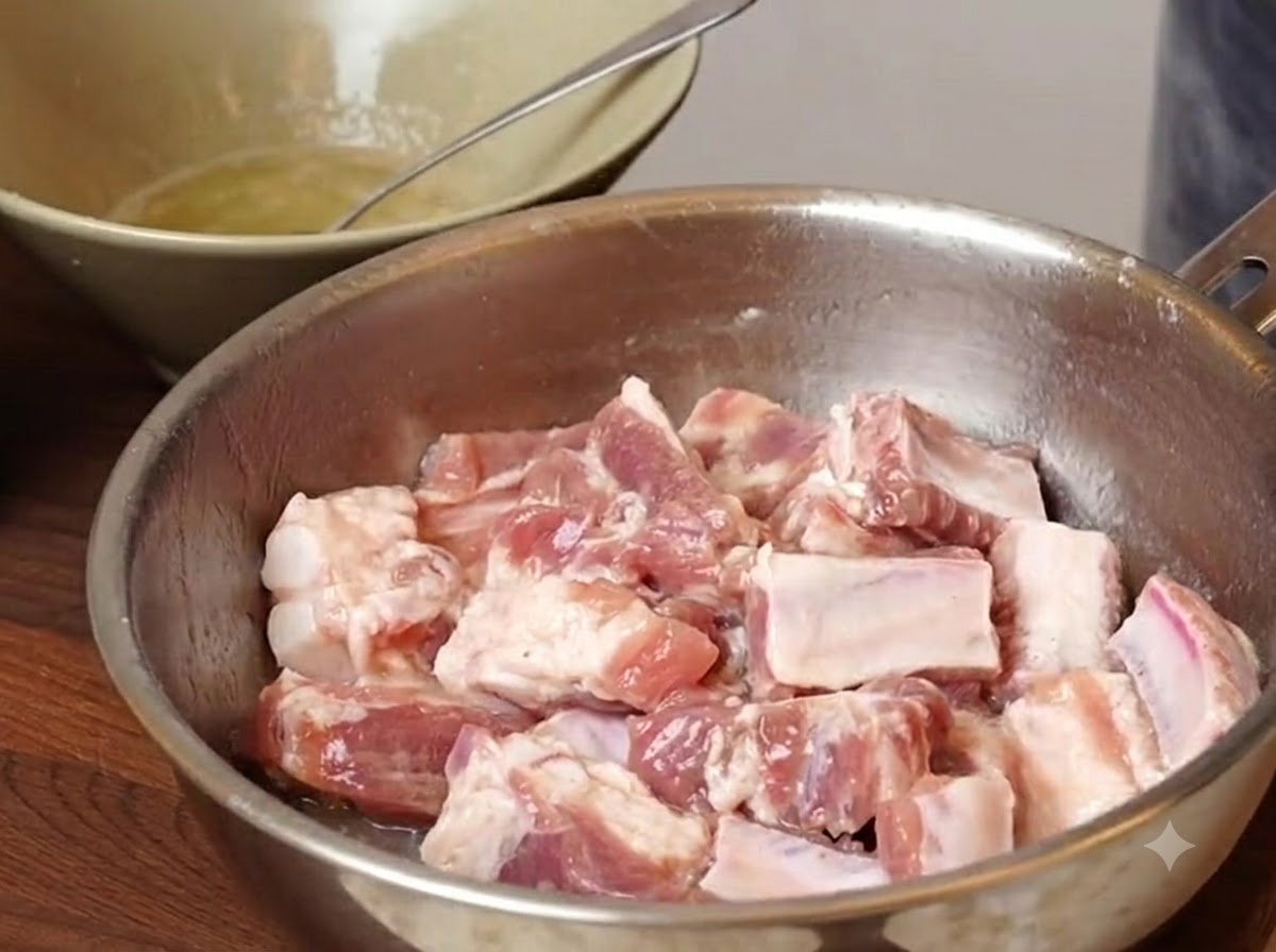 시즈닝과 전분이 뿌려진 금속 볼 안에 담긴 돼지갈비 조각들.
