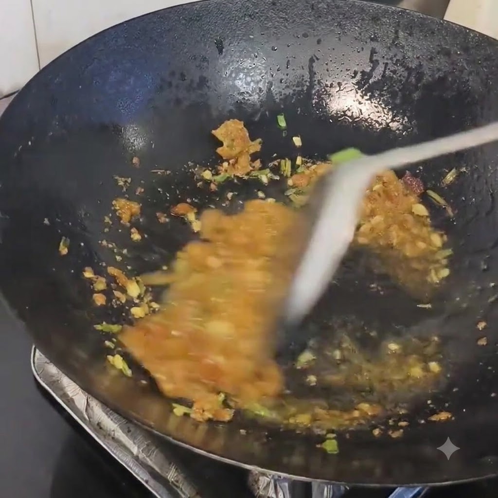 달궈진 웍에서 볶아진 향신 채소에 돼지비계 찌꺼기를 함께 섞고 있는 모습.
