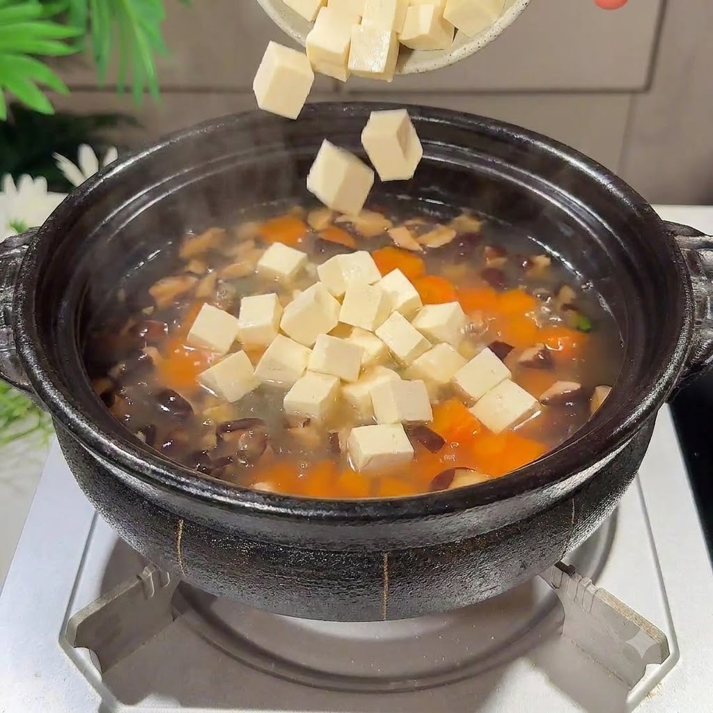끓고 있는 냄비 속으로 깍둑썬 연두부 조각들이 떨어지는 모습.
