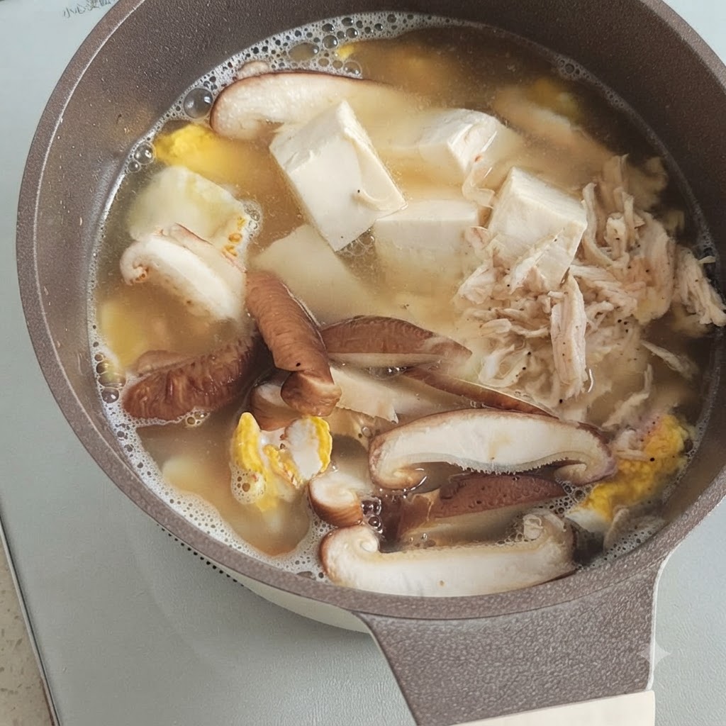 냄비 속 끓고 있는 두부, 버섯, 달걀 위에 올려진 마른새우 한 줌.