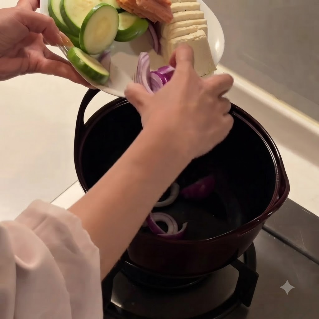 어두운 색상의 냄비 바닥에 썬 적양파를 깔아놓은 모습.