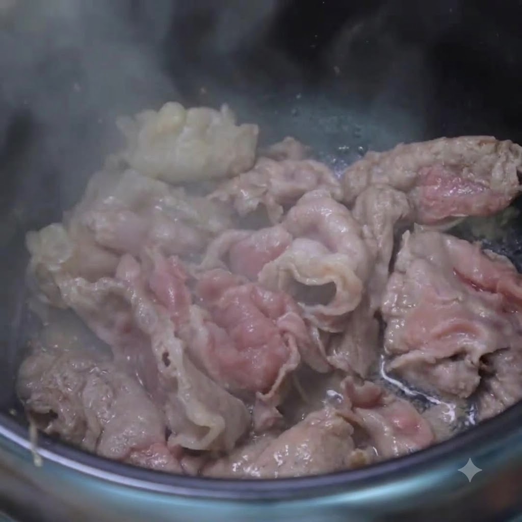 조리용 냄비 안에서 익은 소고기 조각들과 함께 다진 마늘과 썬 대파를 한 숟가락 넣고 볶는 모습.
